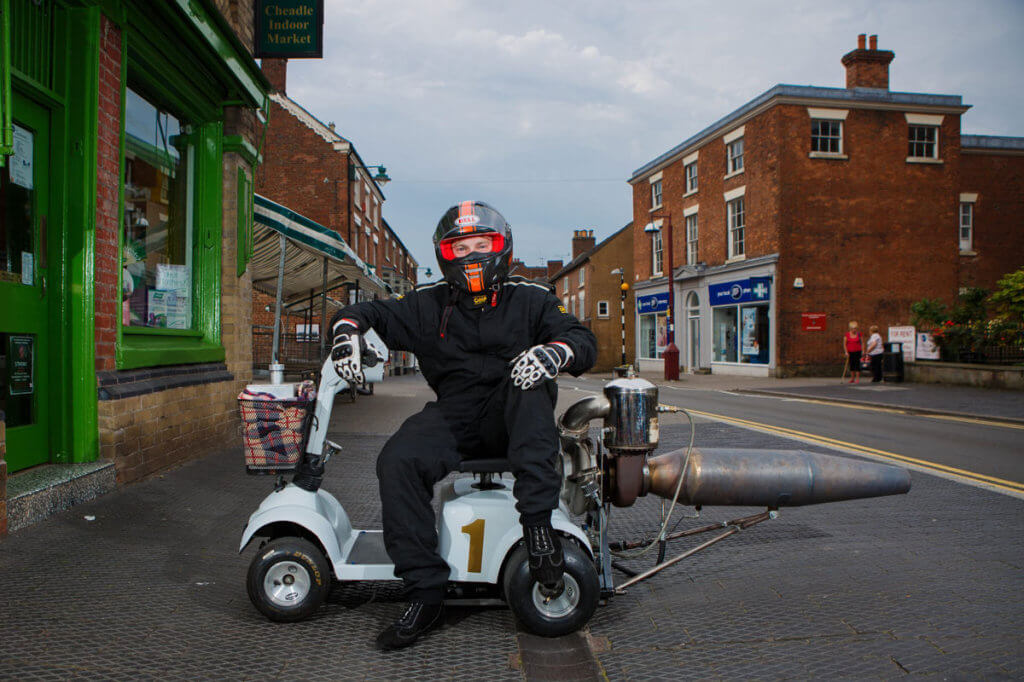 Британский инженер создал реактивный скутер для инвалидов. том бегнелл, дрэг-рейсинг, изобретение, инвалид, реактивный скутер, building, outdoor, road, sky, land vehicle, helmet, wheel, vehicle, person, motorcycle. A man riding a motorcycle on a city street