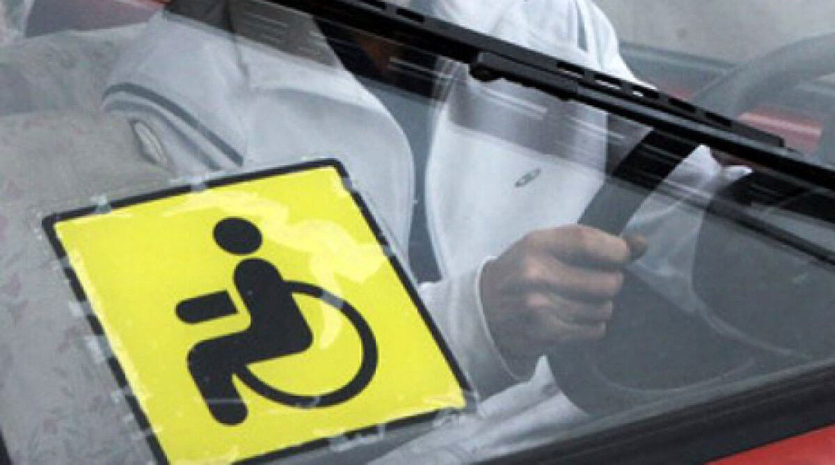 Ввоз автомобилей для людей с инвалидностью освободят от налога. автомобіль, ввоз, забезпечення, оподаткування, інвалідність, person. A person holding a sign