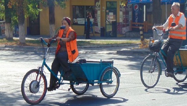 В Мариуполе велорикши помогают людям с ограниченными возможностями (ВИДЕО). мариуполь, свет маяка, велорикша, доставка, инвалидность, outdoor, bicycle, road, street, wheel, person, vehicle, bicycle wheel, land vehicle, cart. A person riding a bicycle on a city street