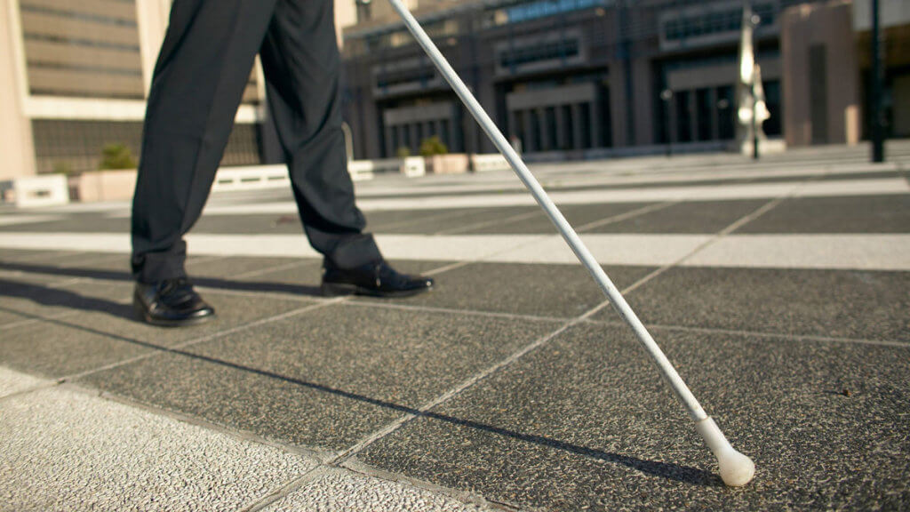 Інвалідність через зір: критерії встановлення та як оформити. мсек, зір, лікар, пацієнт, інвалідність, road, outdoor, trousers, footwear, person, sidewalk, way, jeans, street, clothing. A person standing on a sidewalk